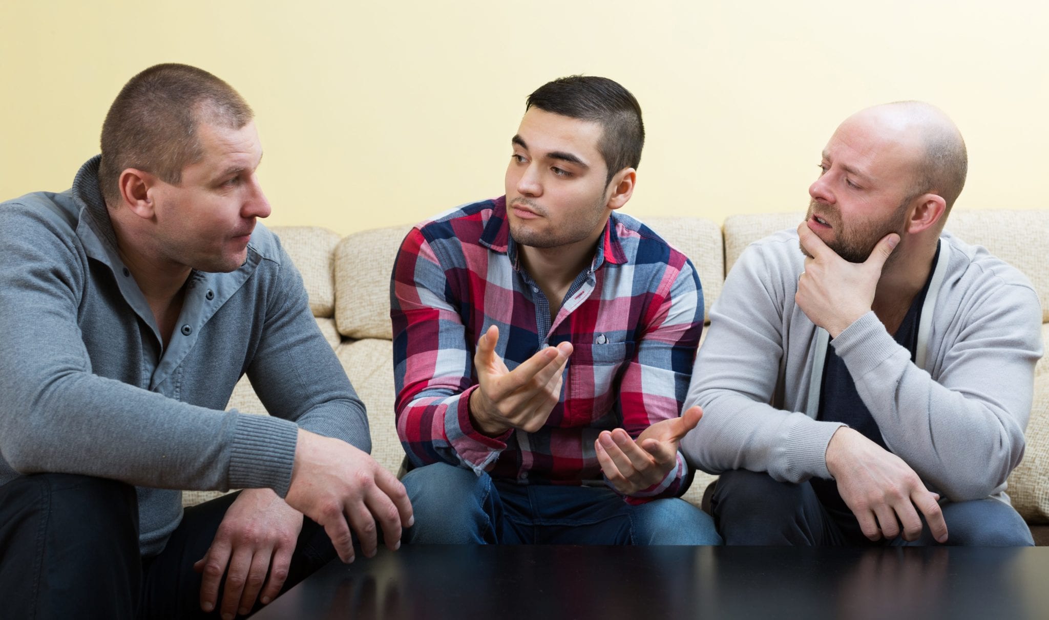 Three sad men having a serious conversation at home